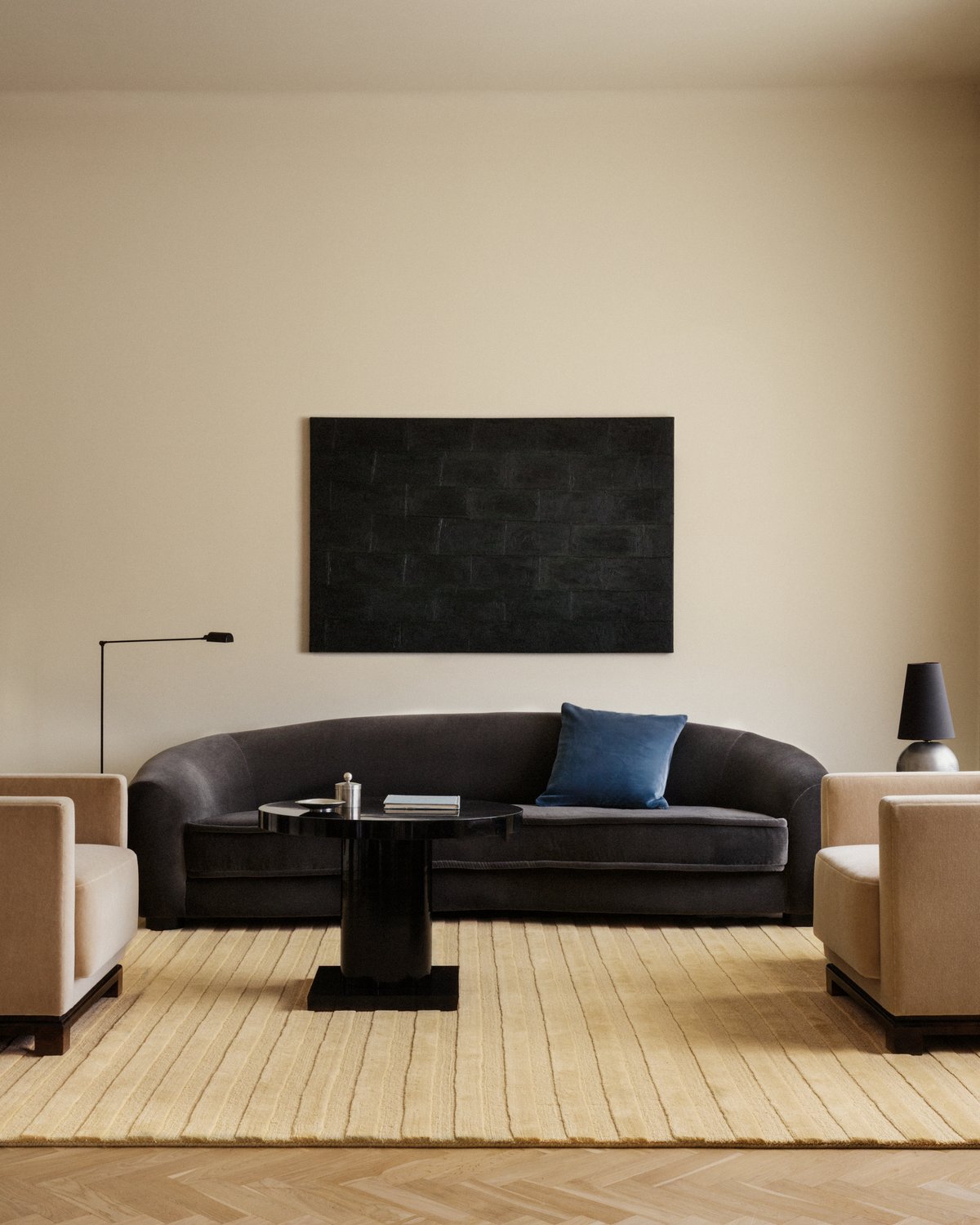 Park 03 rug in Sunrise – a warm golden-toned rug with tonal vertical stripes, grounding a minimalist living room with sculptural seating and a deep-toned sofa.