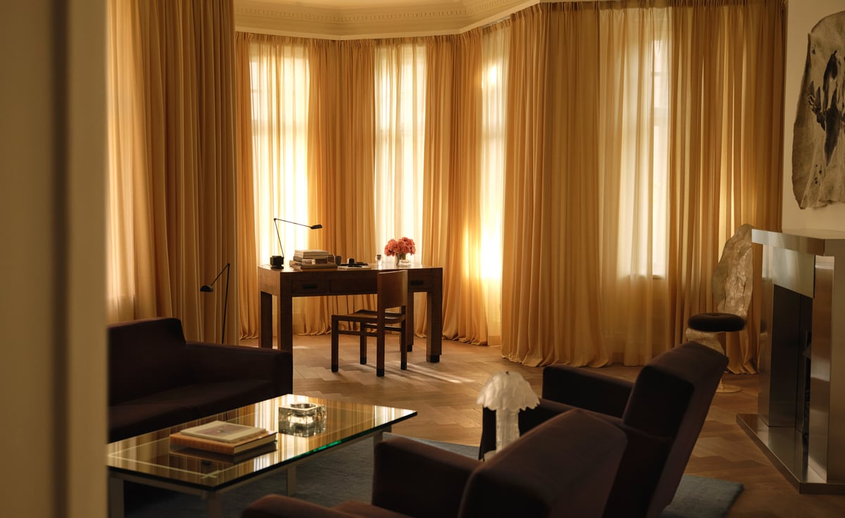 The Grand curtain in Sunrise — a softly woven curtain in a warm golden tone, with a smooth surface and fluid drape, falling in long, elegant folds and filtering light to create a glowing, ambient effect.