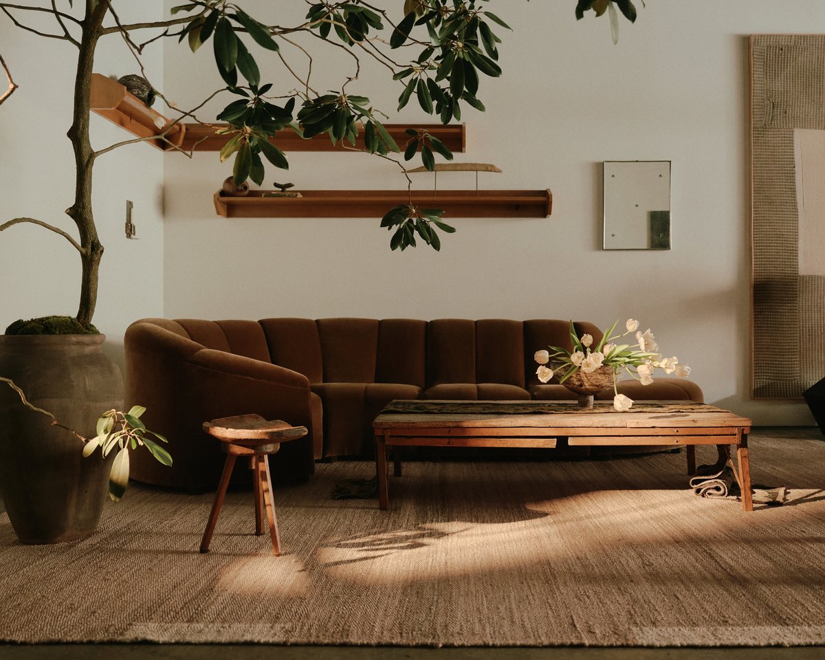 Jute rug Edge Cream pictured in a cozy living room with neutral colored furniture and large plants at studio WAS in New York.