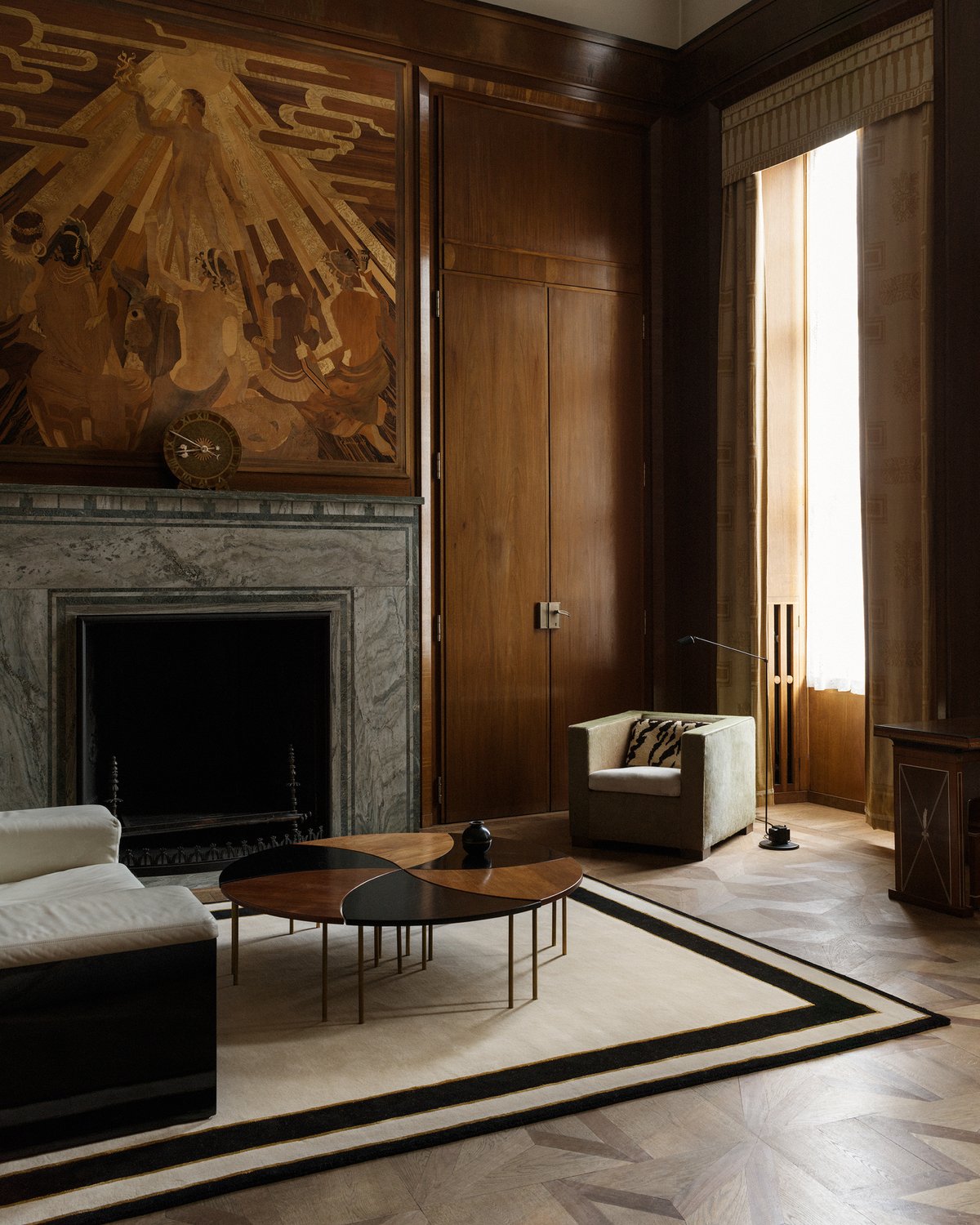 Flauschiger Wollteppich Gild 01 Frame abgebildet in einem herrschaftlichen Wohnzimmer mit einem Holzrelief über einem großen Marmorkamin.