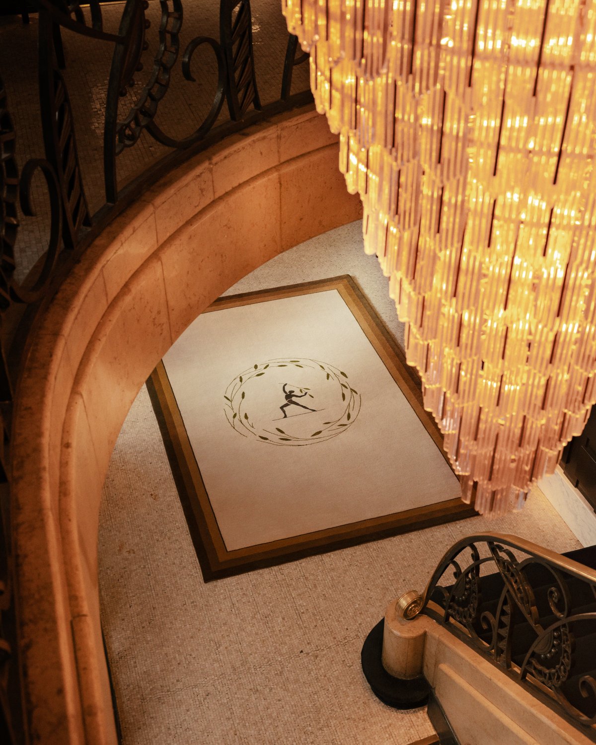 Plush wool rug designed by Parisian designer Fabrizio Casiraghi on a marble floor next as seen looking down from a beautiful staircase next to a large chandelier in Paris, France
