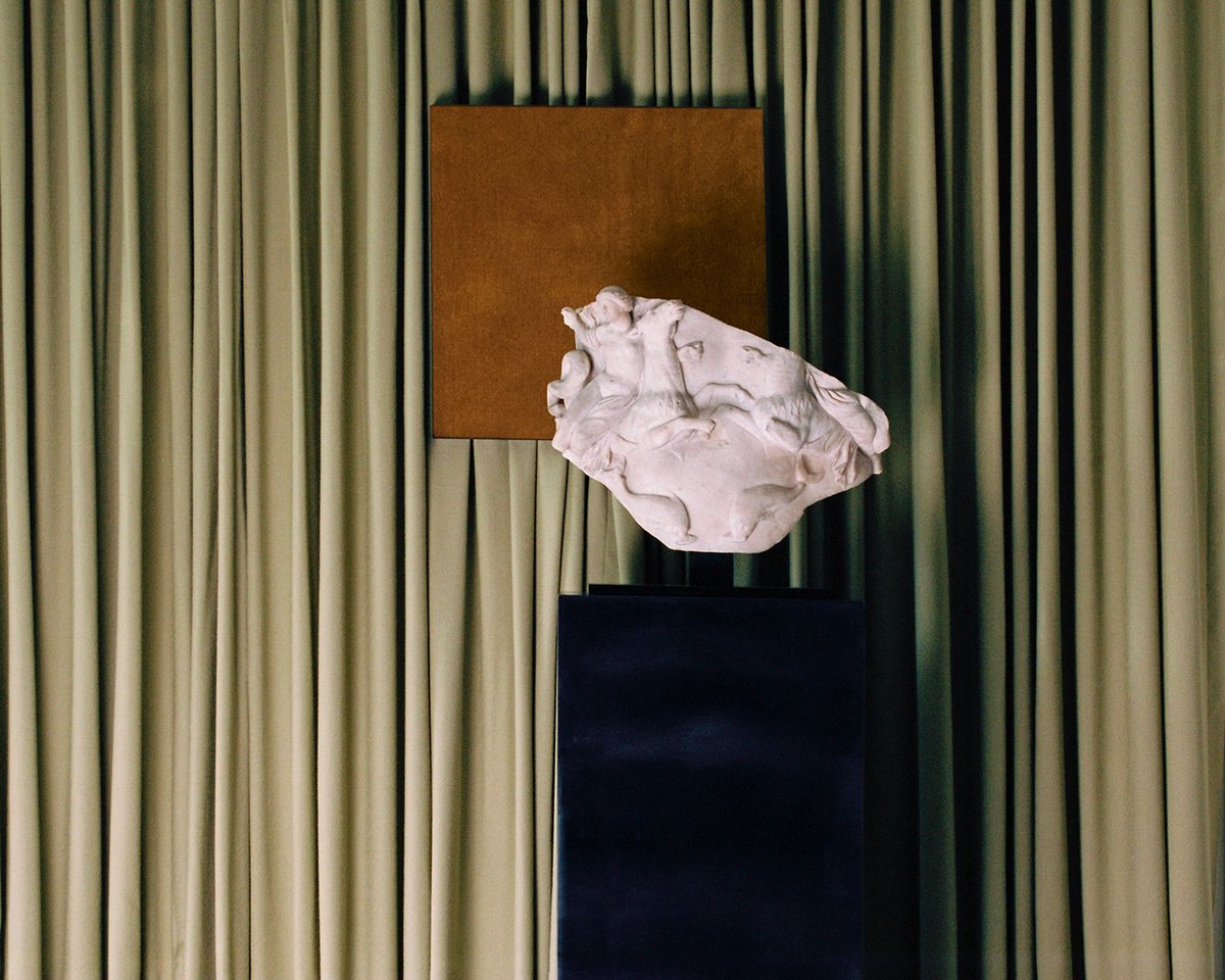 The Grand curtain in Pale Green and a painting of the Grand rug in Leo displayed behind a marble statue at Galerie Chenel in Paris.