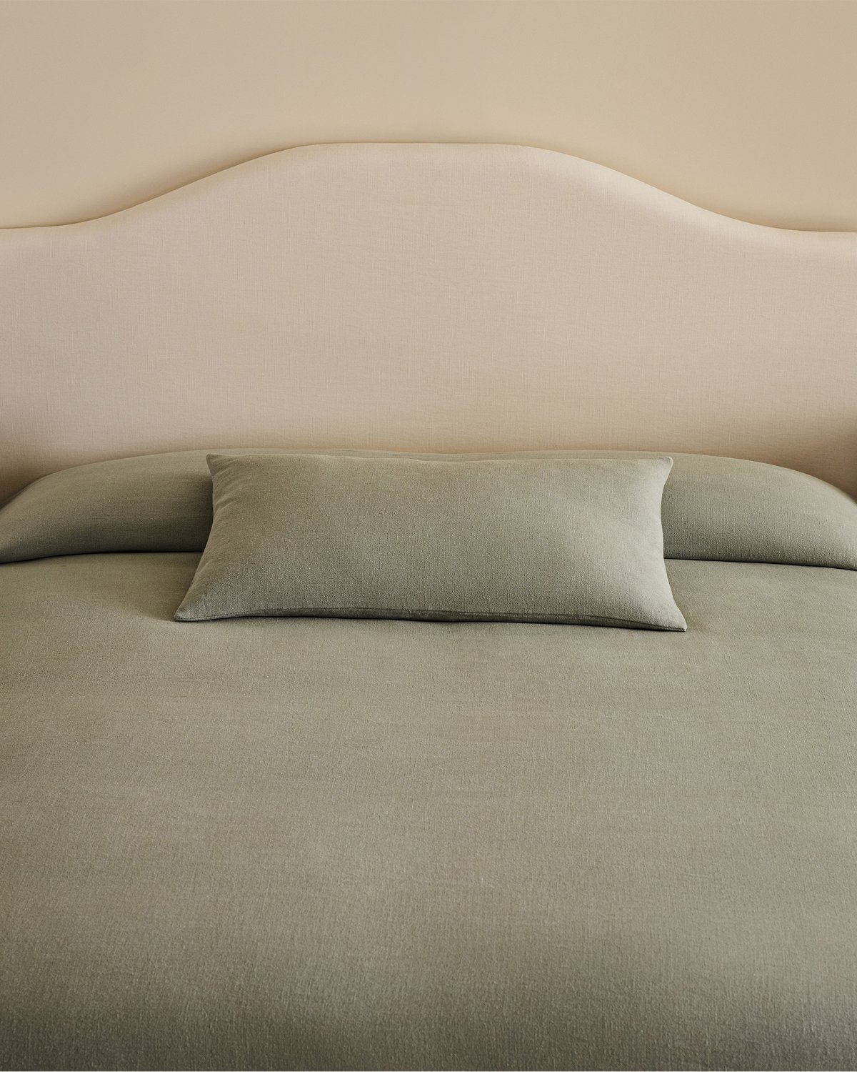 Gros plan sur la tête de lit Crown en Warm White associée au couvre-lit Studio Linen en Lagoon, créant une ambiance de chambre douce et raffinée aux textures naturelles et aux tons apaisants.