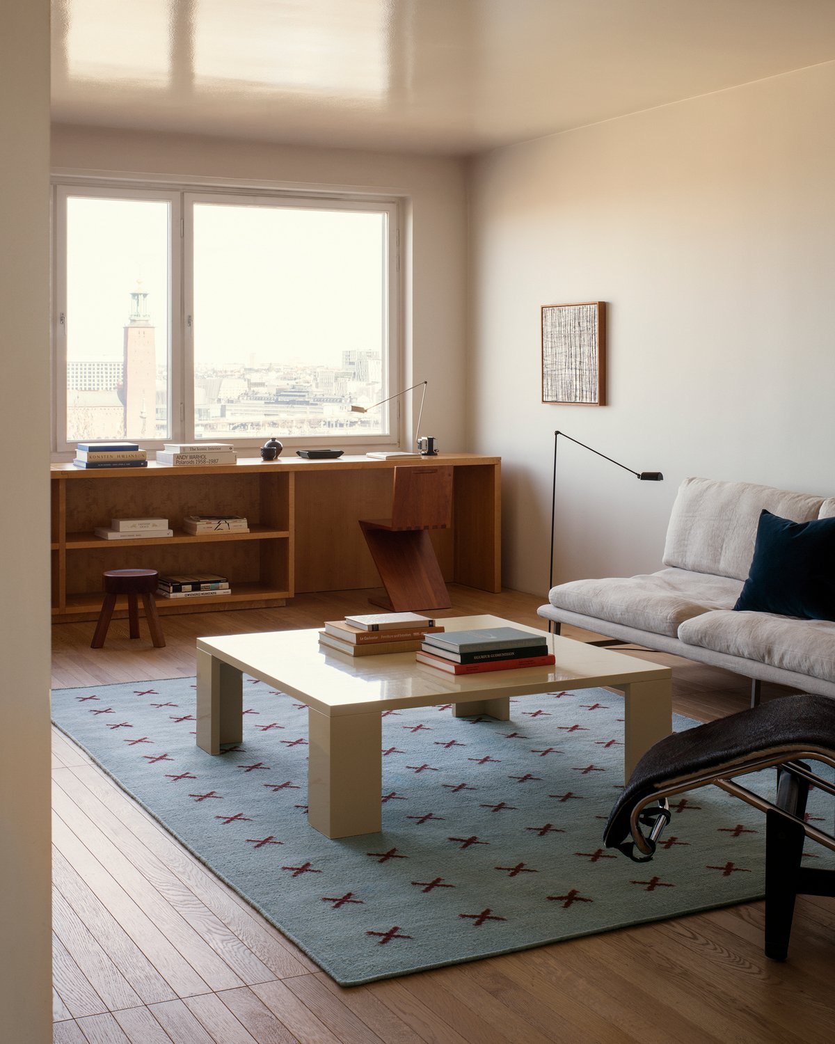 Cross rug in Blue/Burgundy featured in a light living room in Stockholm, Sweden. The flatweave rug is displayed underneath a yellow coffee table, next to a light gray sofa.