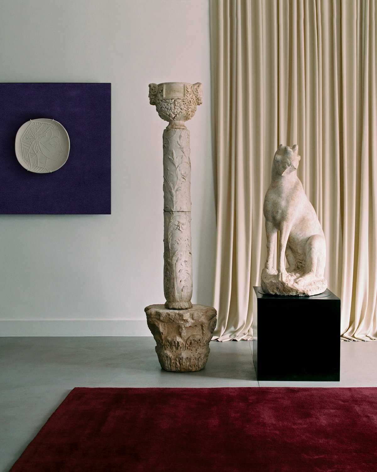 Le rideau Grand en Pale Sand et le tapis Grand en Deep Wine exposés dans une salle avec des sculptures, accompagnés d’une peinture du tapis Grand en Lilac à la Galerie Chenel à Paris.