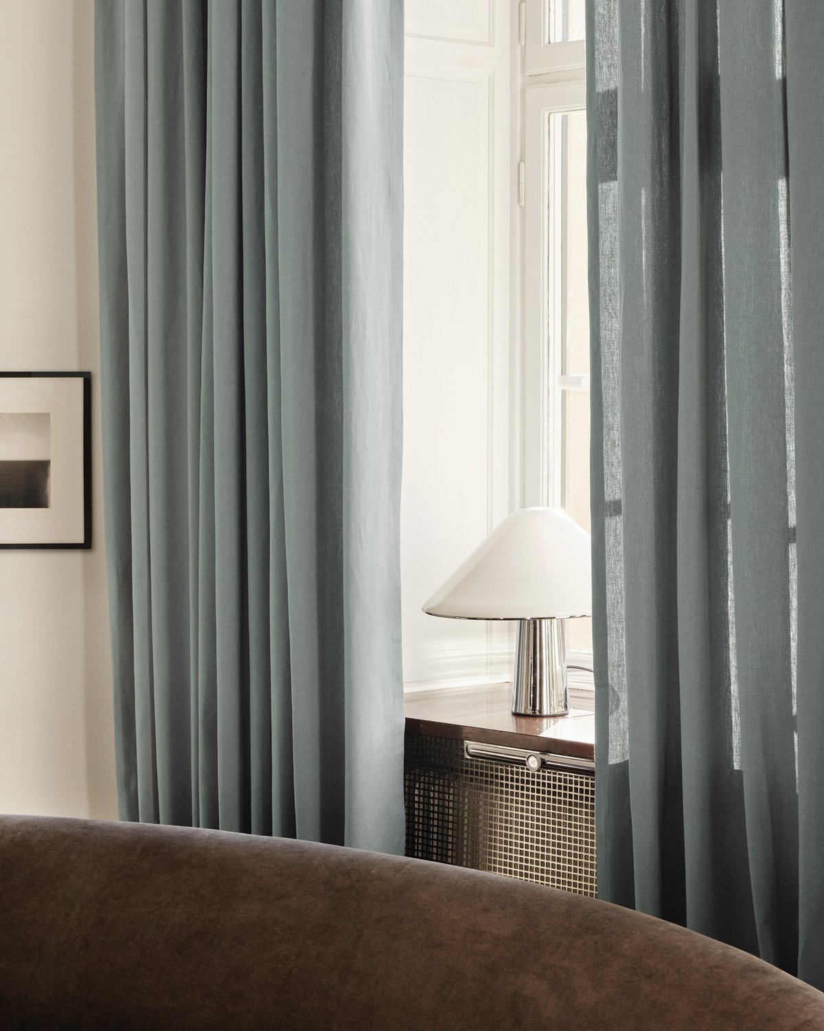 The Grand wool curtains in Pale Blue framing a window in a light living room.