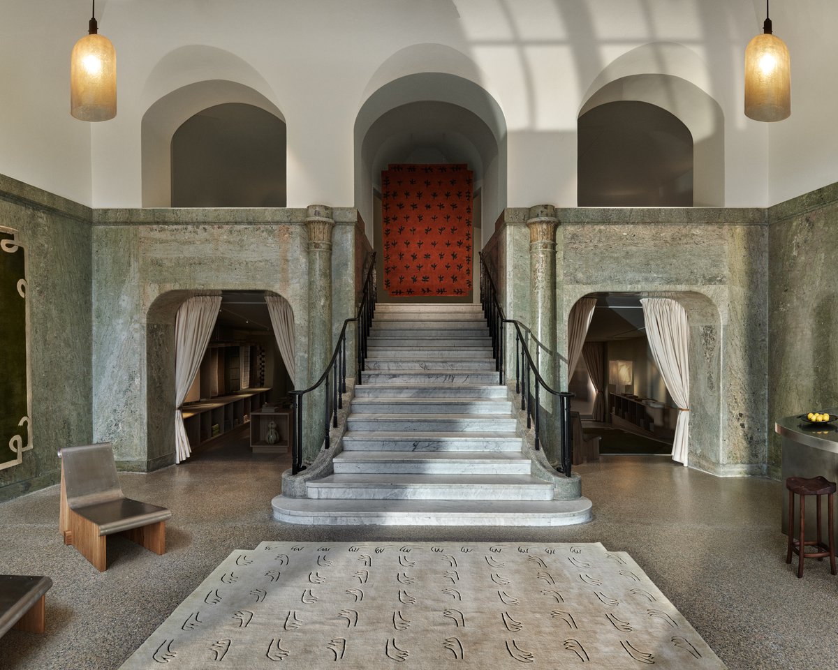 Stockholm Flagship store entrance staircase with the All Hands Beige rug in the foreground, and the Big Buds rug hanging on the second floor above the stairs.