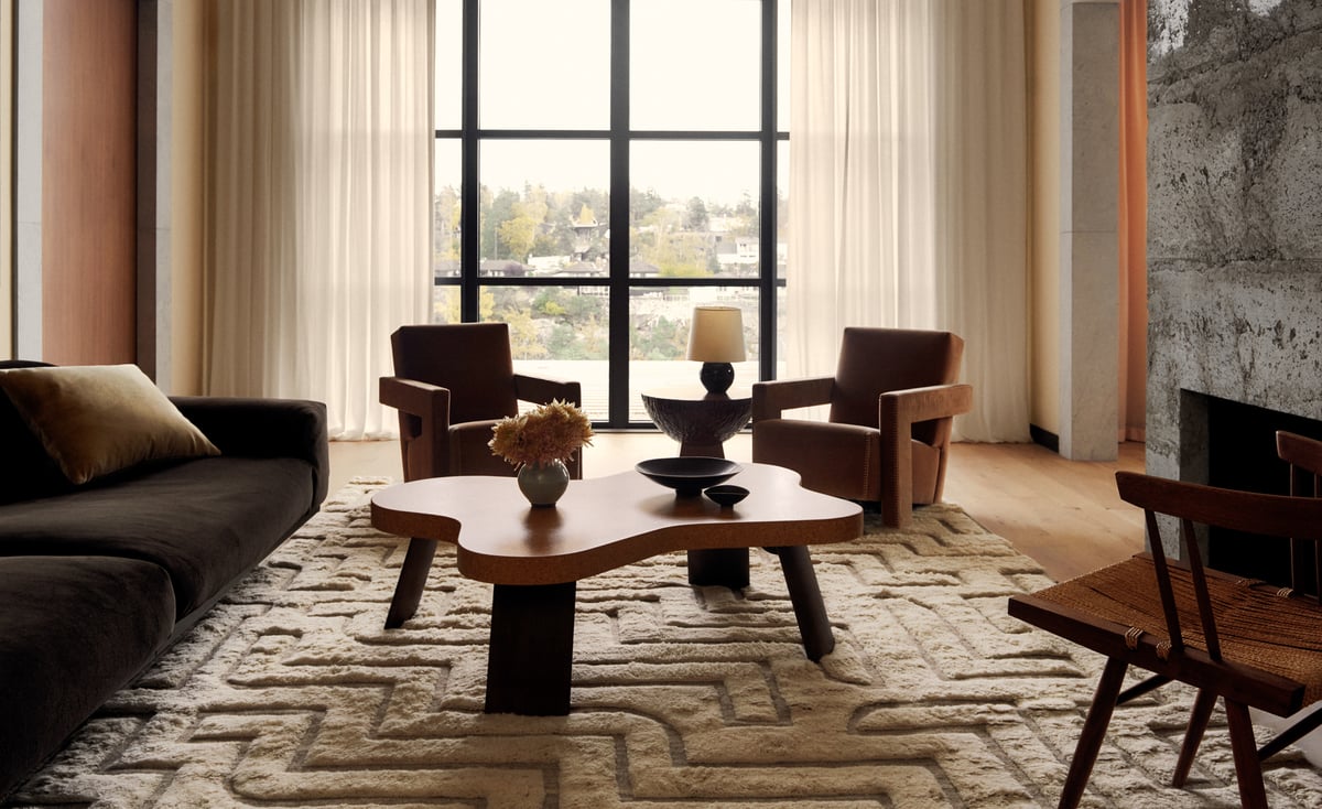 The Boho 02 – Shearling rug in a refined living room with large windows and natural light. Styled with sculptural furniture in warm wood tones for a serene, modern feel.