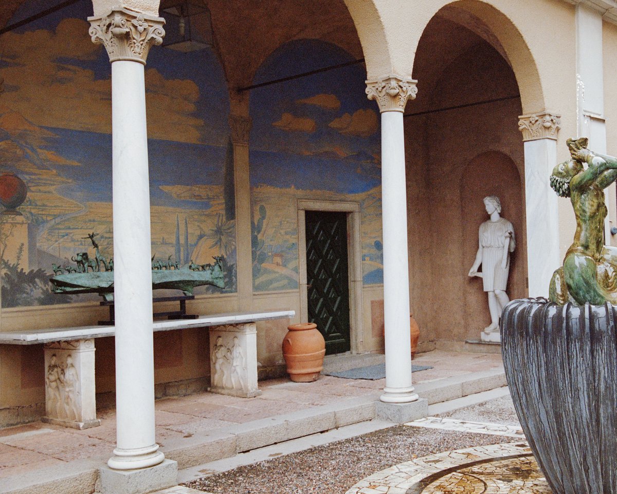 Bild av sidan på en byggnad i en innergård med stenpelare och färgglada väggmålningar.