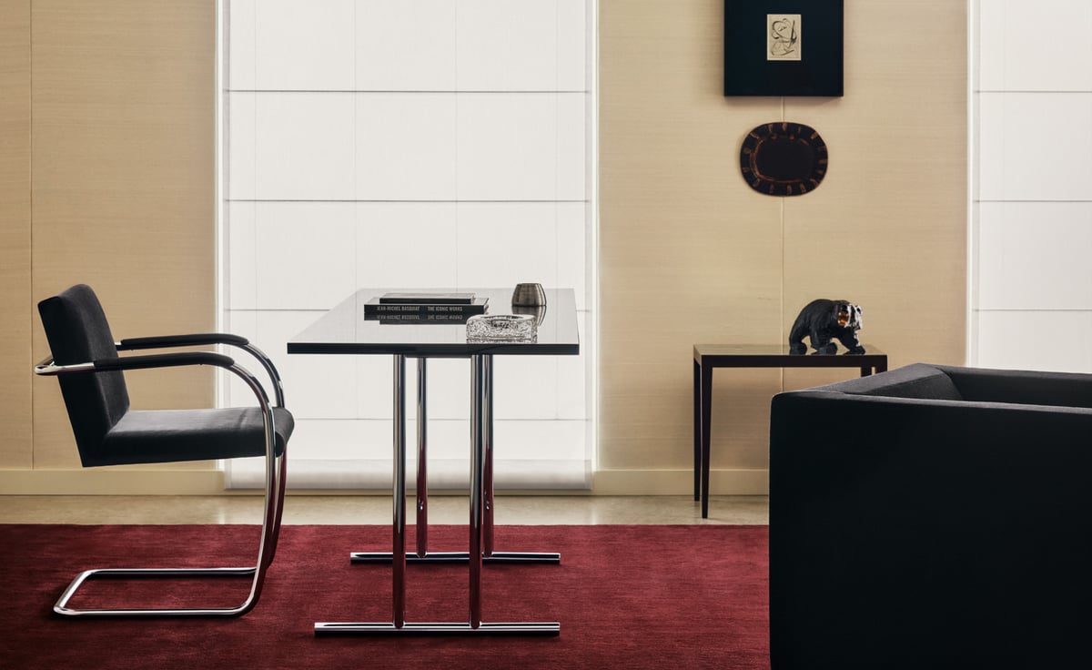 Mattan The Grand i Deep Wine, stylad i en sofistikerad miljö med kromade stolar, ett minimalistiskt bord och varma beige väggar som skapar en rik och dramatisk kontrast.