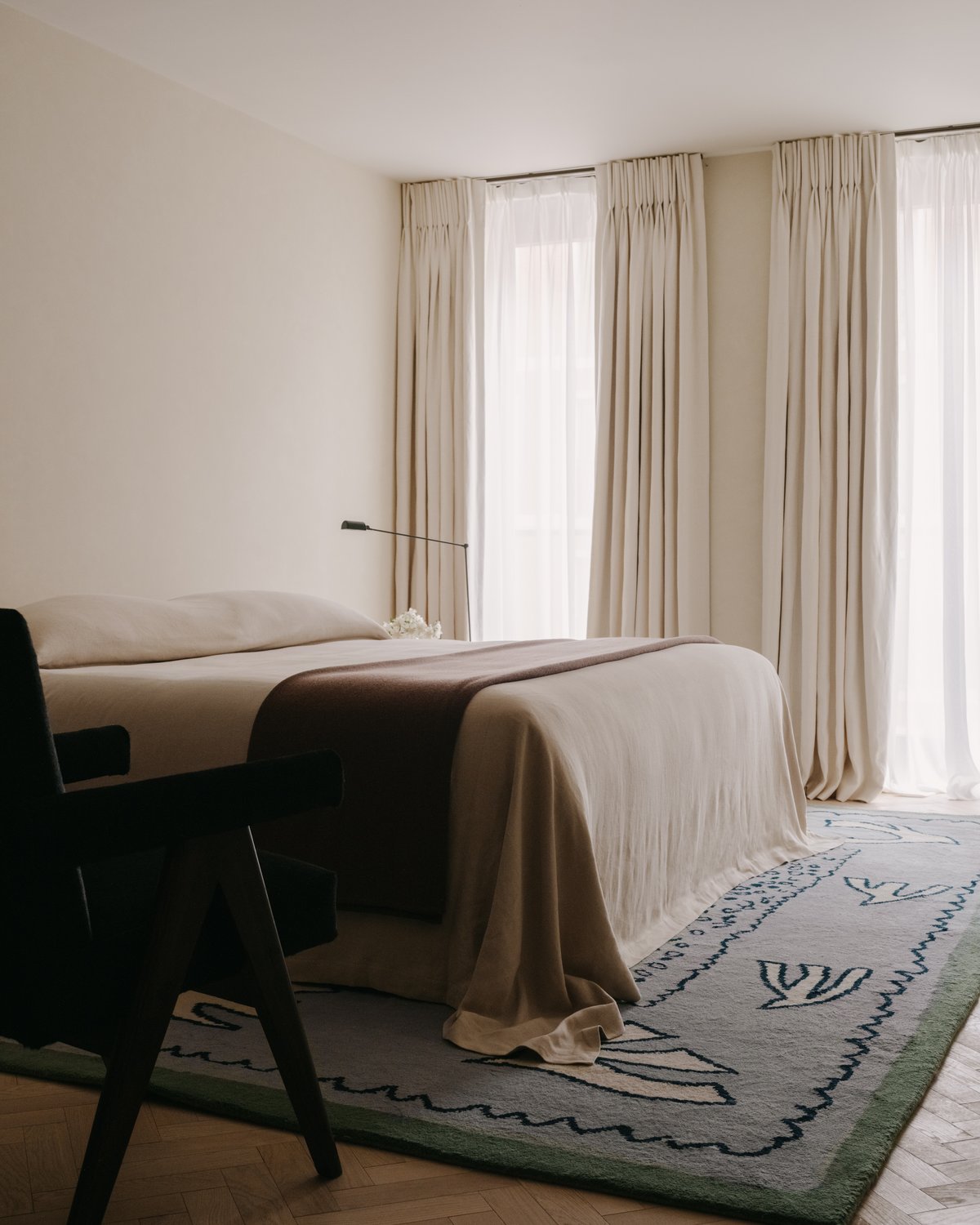 Serene bedroom with soft beige tones, a neatly dressed bed, and the Columba – Blue rug featuring geometric leaf motifs.