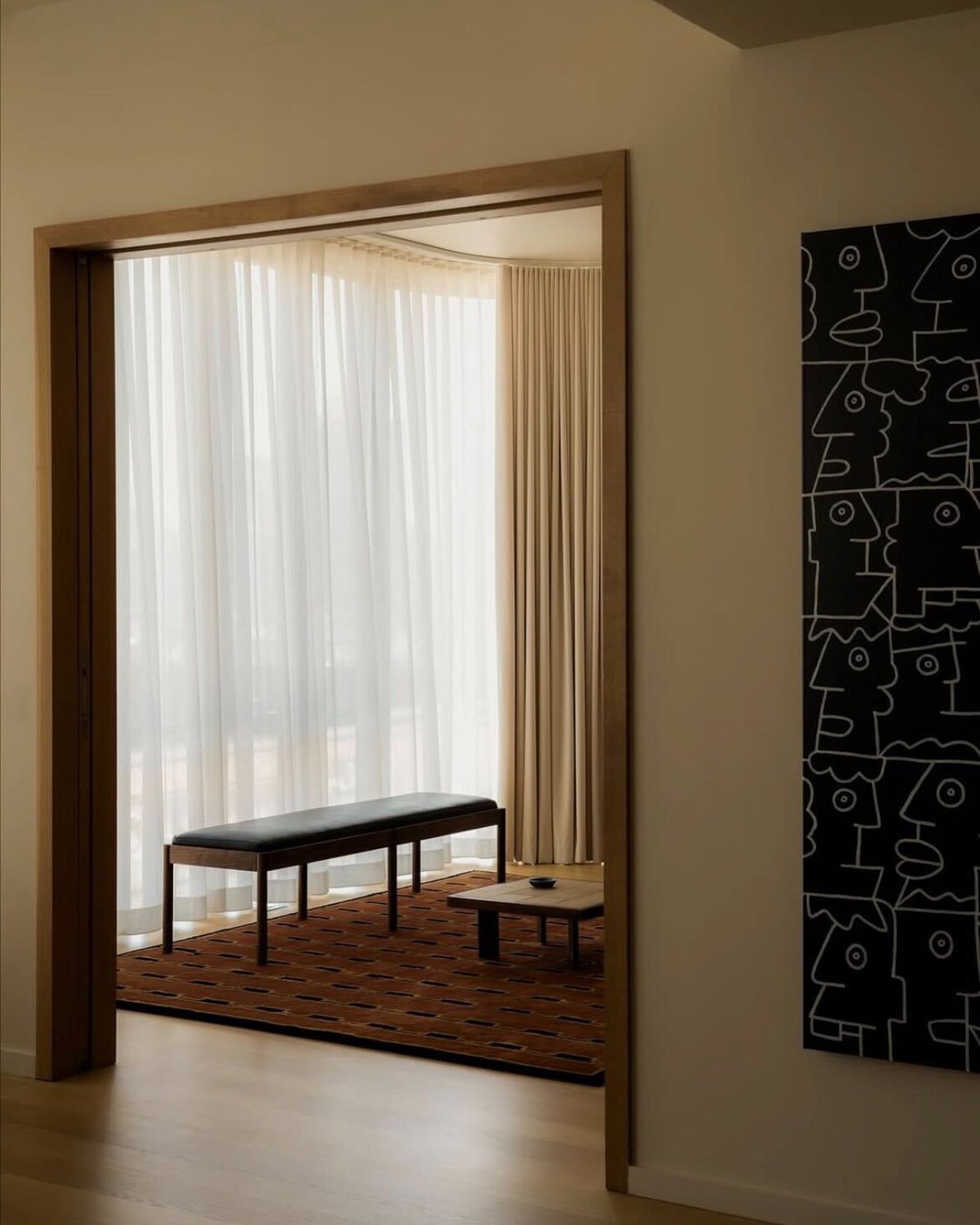 Gild 02 in Red, photographed in a softly lit room beneath sheer curtains and a bench.