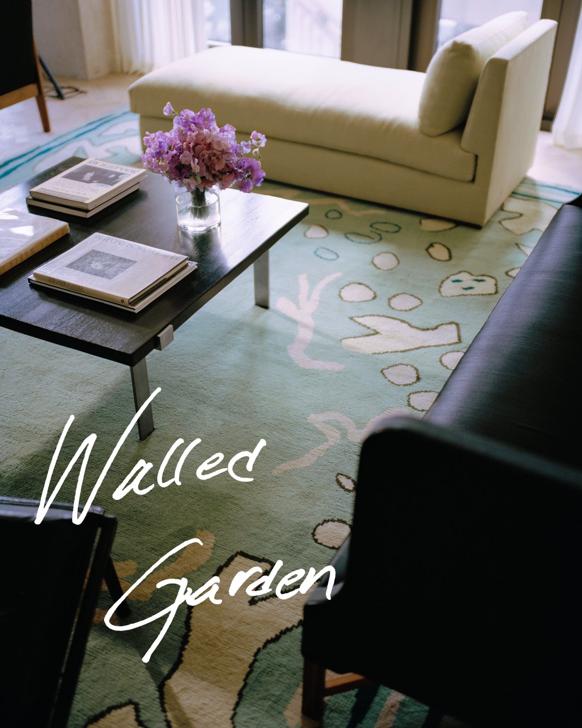 Giverny in Green in a bright living room with large windows. Styled with a black coffee table, a light chaise longue and a dark sofa.