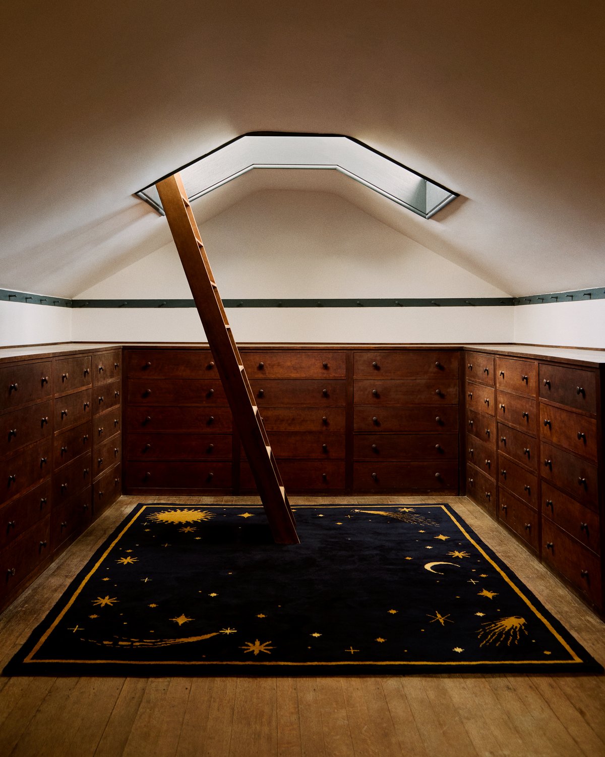 Plush wool rug Celestial in collaboration with ASH pictured in an attic space with wooden drawers and latter.