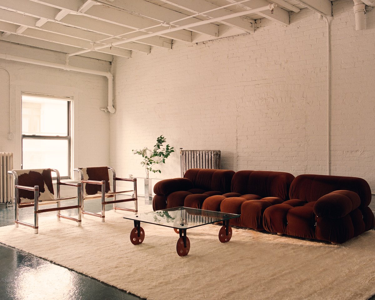 Fields Dusty White pictured in a white industrial apartment with modern chairs and red couch.