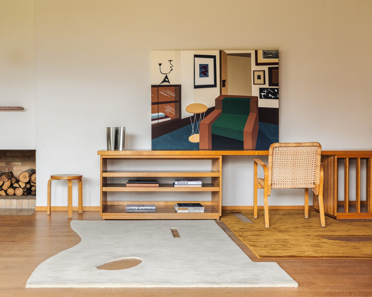 Garance Rug in Dusty White and Garance Rug in Leo layer together in a soft, sculptural space, blending creamy tones and bold pattern to add warmth and quiet character to a space with a wooden table and chair.