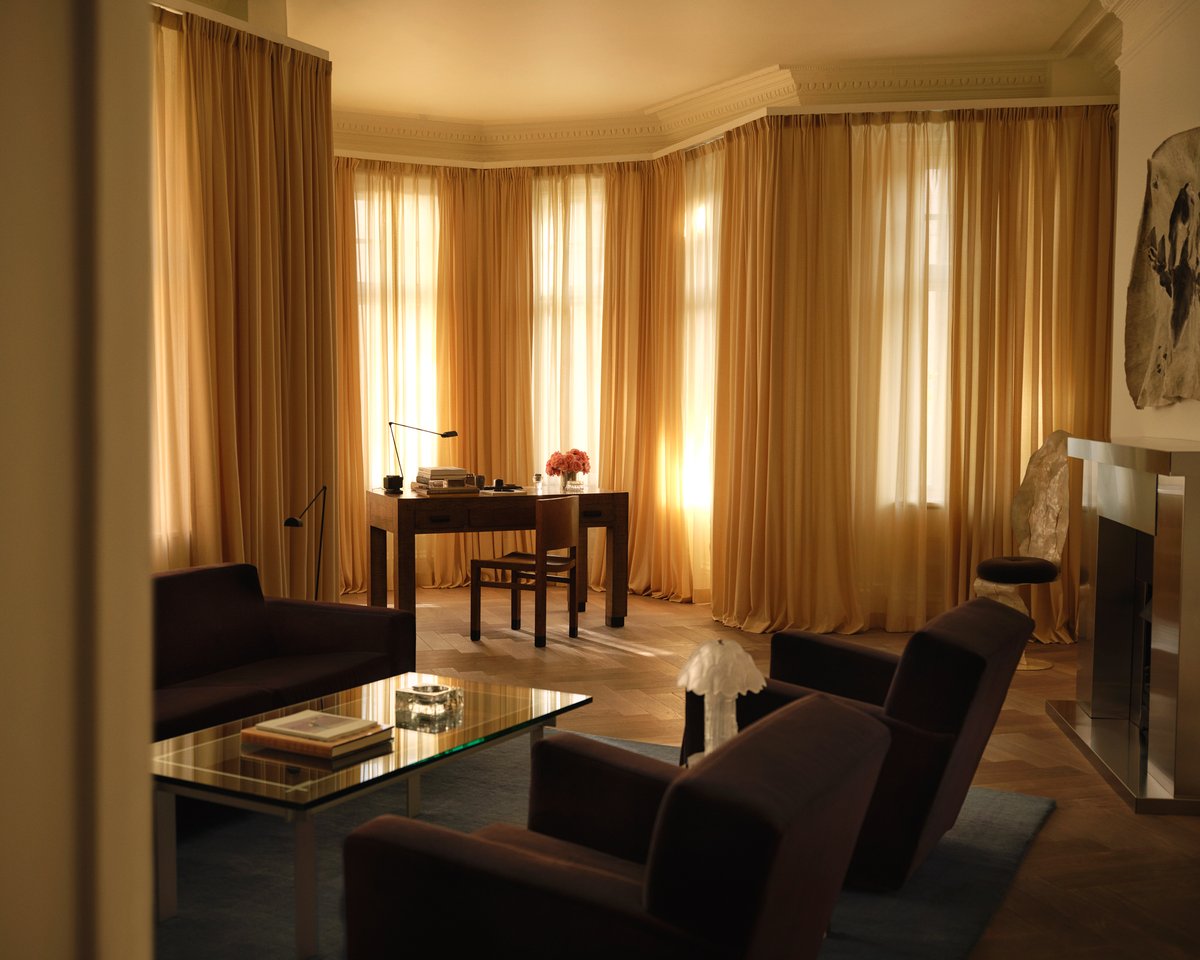 The Mohair rug in Slate Blue is shown in the Nordic Knots store on Mount Street in London, styled with dark velvet furniture, The curtains in Leo, and a glass coffee table, creating a refined and contemporary atmosphere.