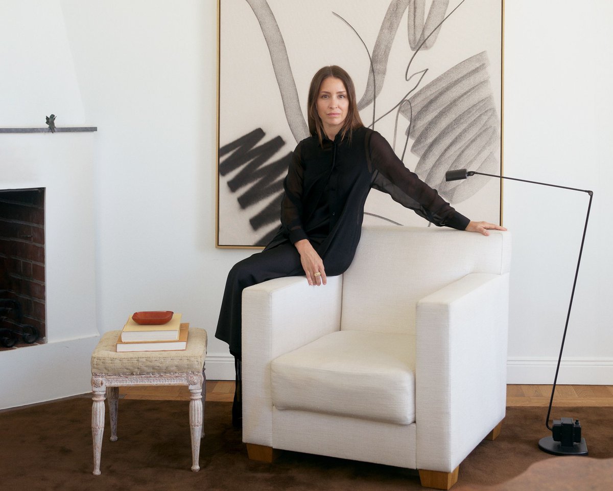 Founder Liza pictured by a white armchair with plush wool rug Grand in Walnut featured.