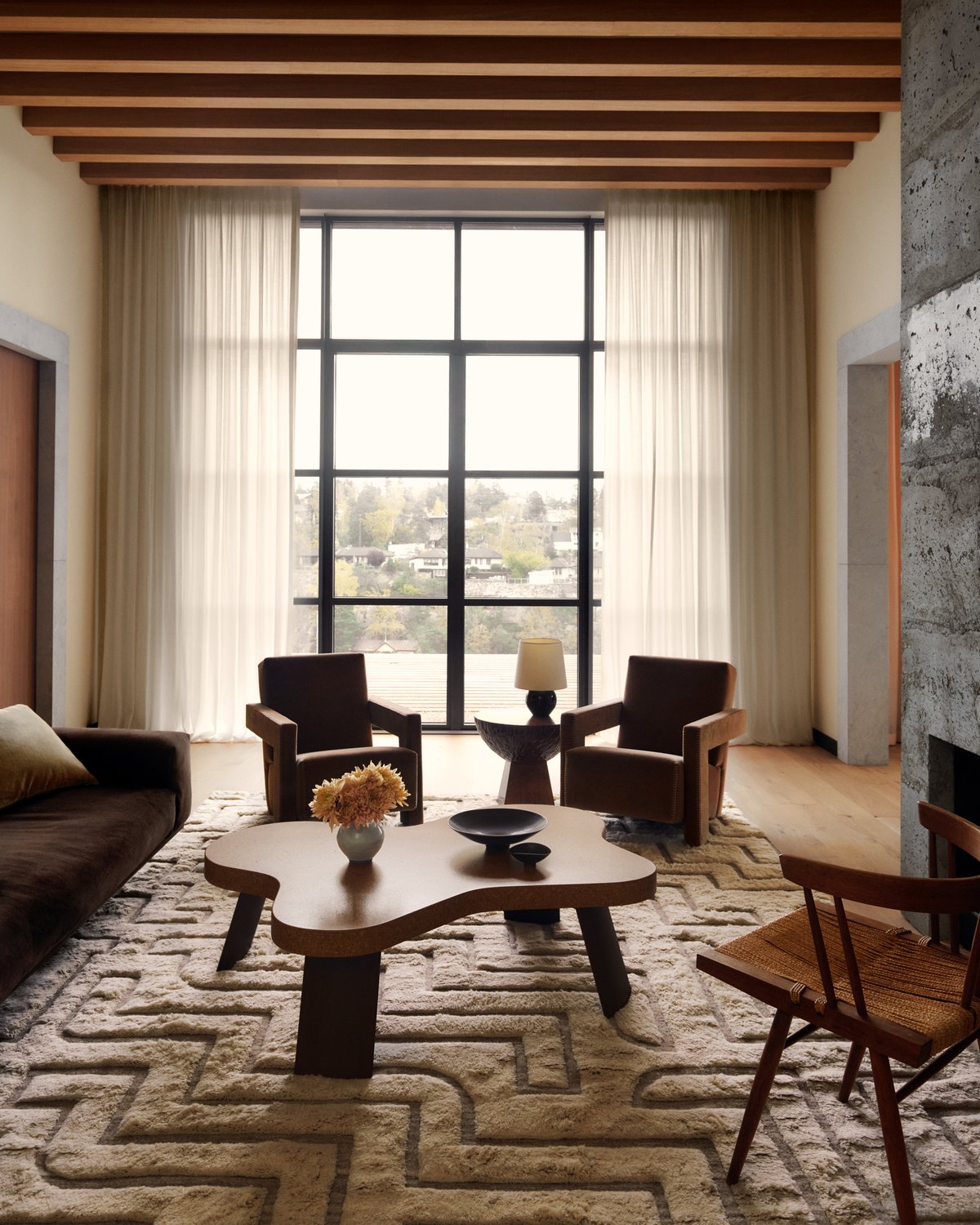 The Boho 02 – Shearling rug in a refined living room with large windows and natural light. Styled with sculptural furniture in warm wood tones for a serene, modern feel.