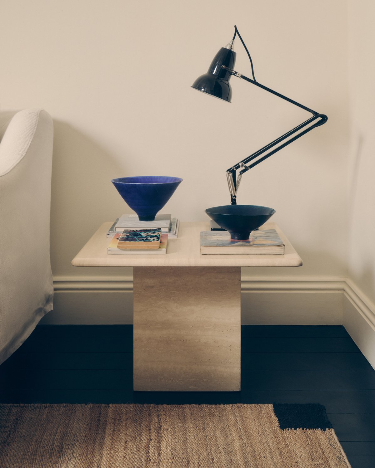 Tapis en jute Corner Black photographié près d’une table basse carrée ornée d’une lampe noire et de bols en céramique.