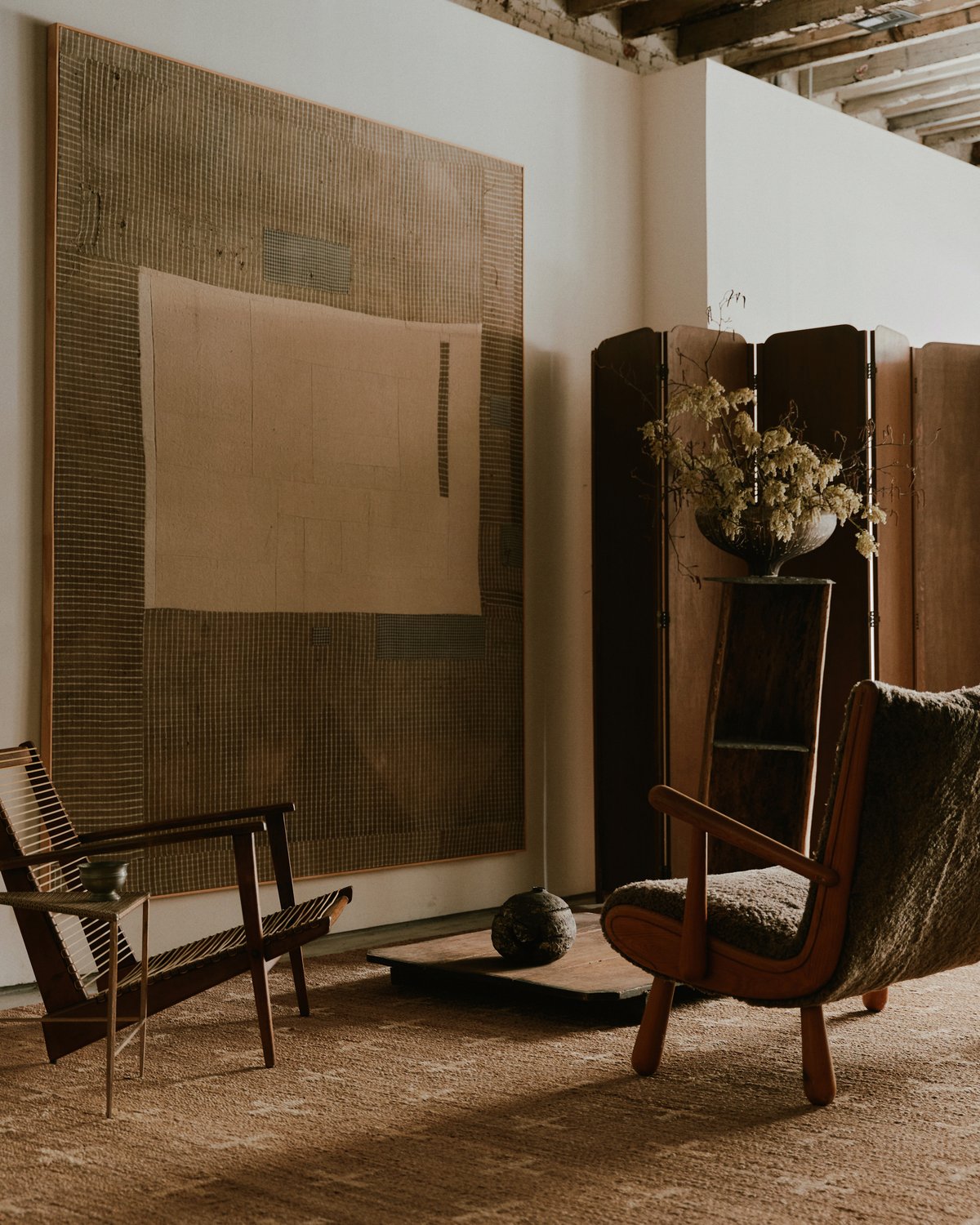 Juteteppich Cross Cream, abgebildet in einer Zen-Sitzecke mit Holzmöbeln und einem großen Gemälde im Studio WAS in New York.