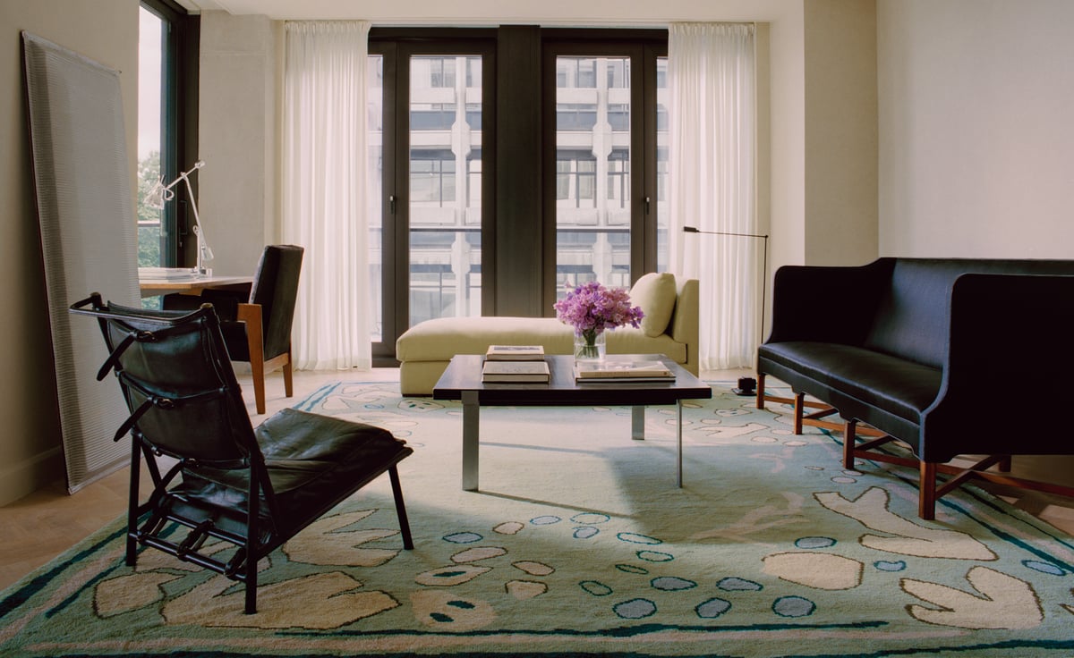 Giverny in Green photographed in a bright living room with tall windows. Styled with modern seating in dark accents.