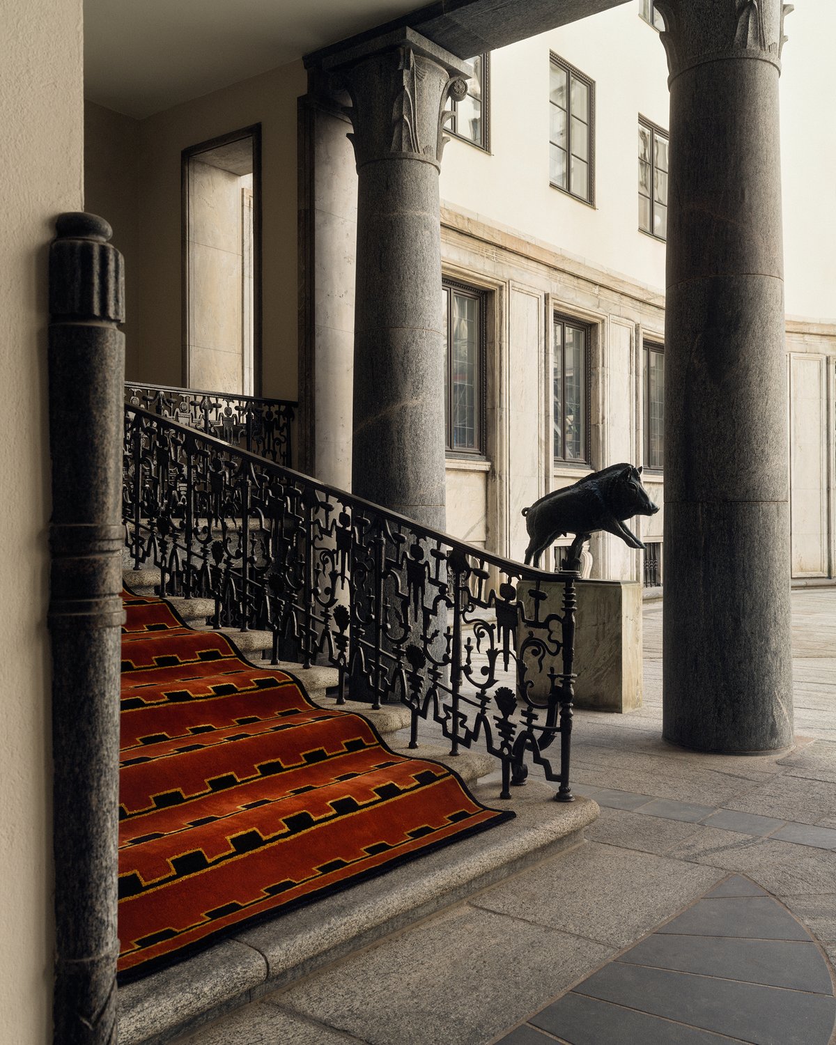 Plush wool rug Gild 02 pictured on a grand stone staircase at the side of a building with tall stone pillars.