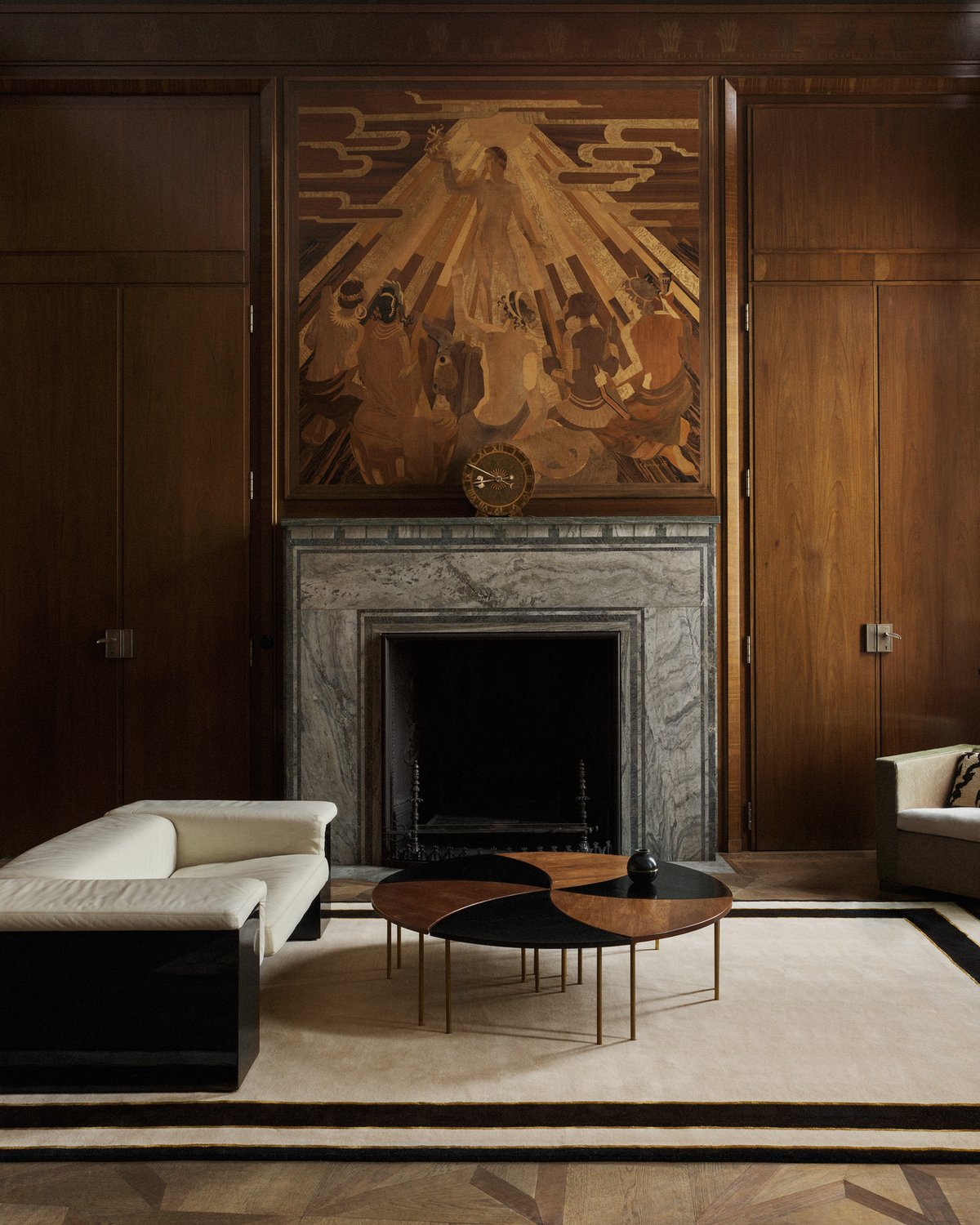 Plush wool rug Gild 01 pictured in an elegant living room with tall wood walls and a grand marble fireplace.