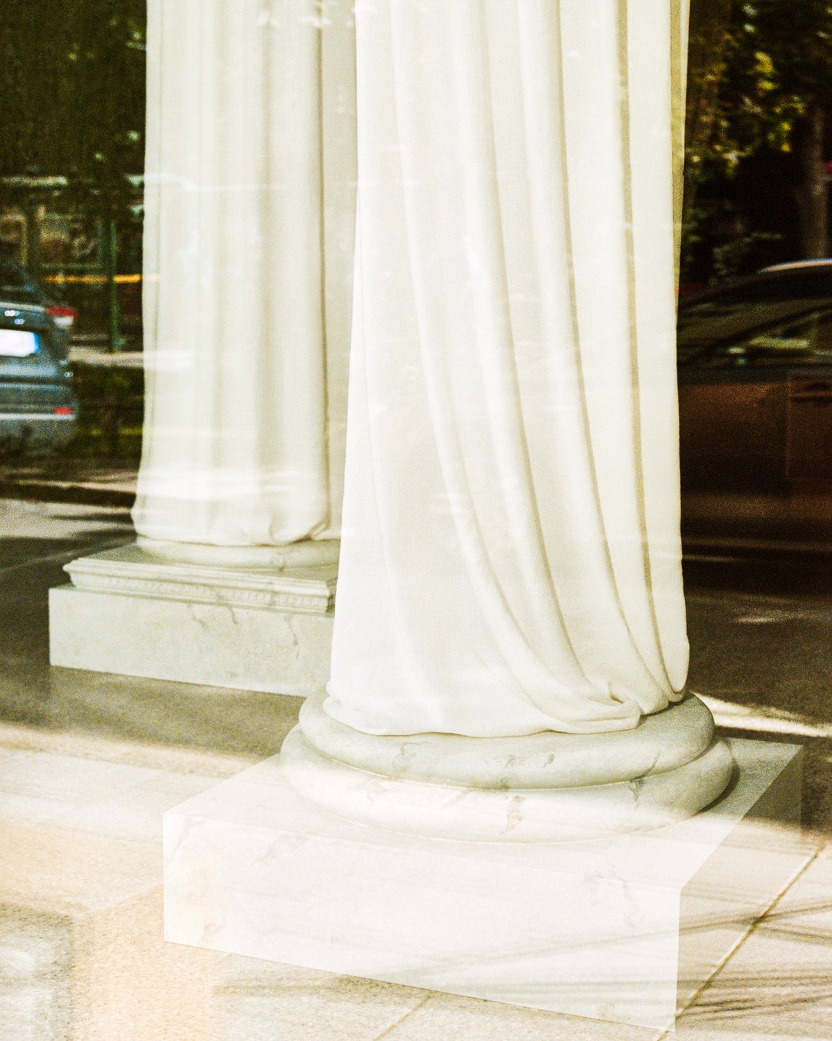 The Grand curtains depicted through the window of the Stockholm Flagship store with the sunlight reflecting off of the green marble floor interior.