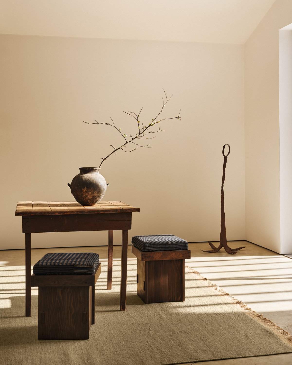Desert – Fern, présenté dans une pièce lumineuse avec une table en bois. Le tissage plat et les franges en jute sont visibles.