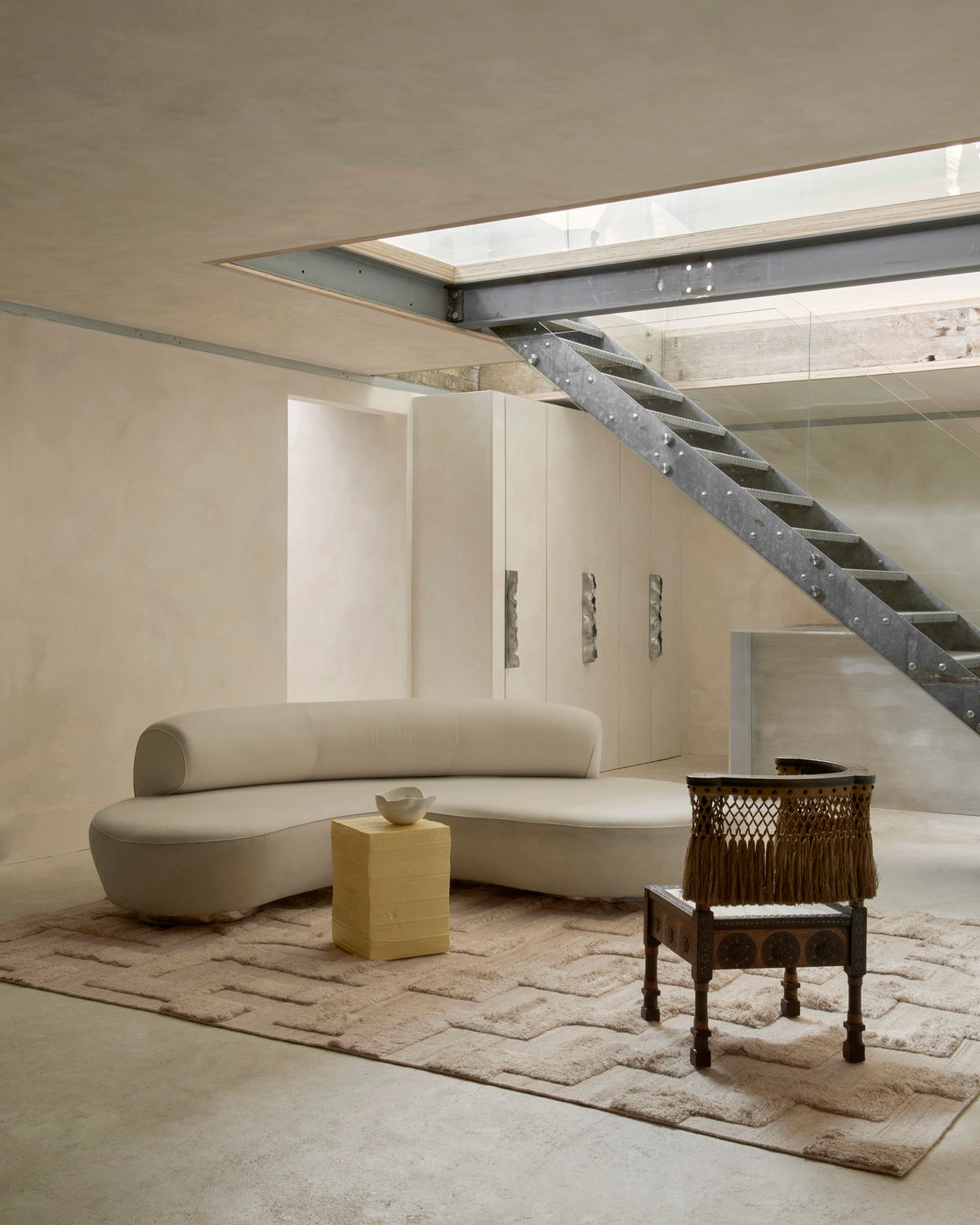 Shaggy-Wollteppich Boho in Sand Mix, abgebildet in einem Lounge-Raum im modernen Brutalismus-Stil mit architektonischen Metalldetails und einem weichen weißen Sofa in London.