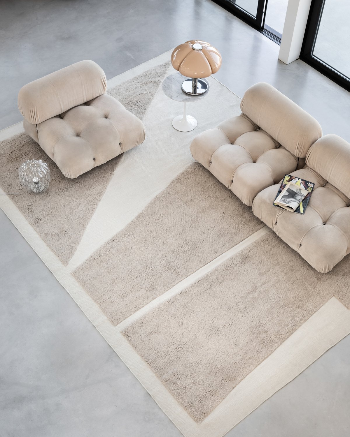 Tapis en laine moelleux Untitled 02 photographié depuis un escalier avec un ensemble de canapés beiges dans une pièce moderne.