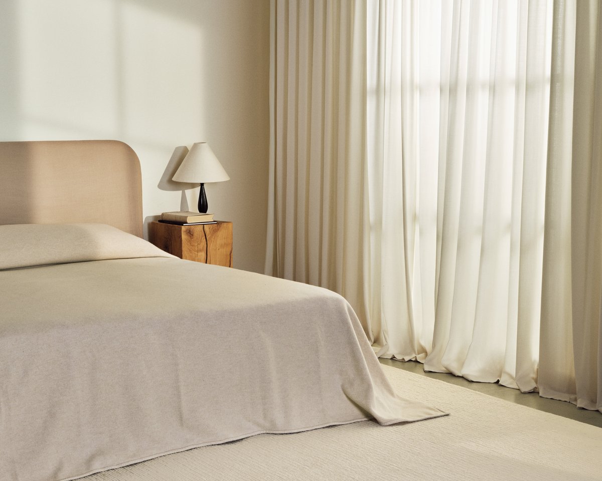 Flatweave wool rug Braid in Cream pictured in a bedroom with cream colored curtains and matching bed.
