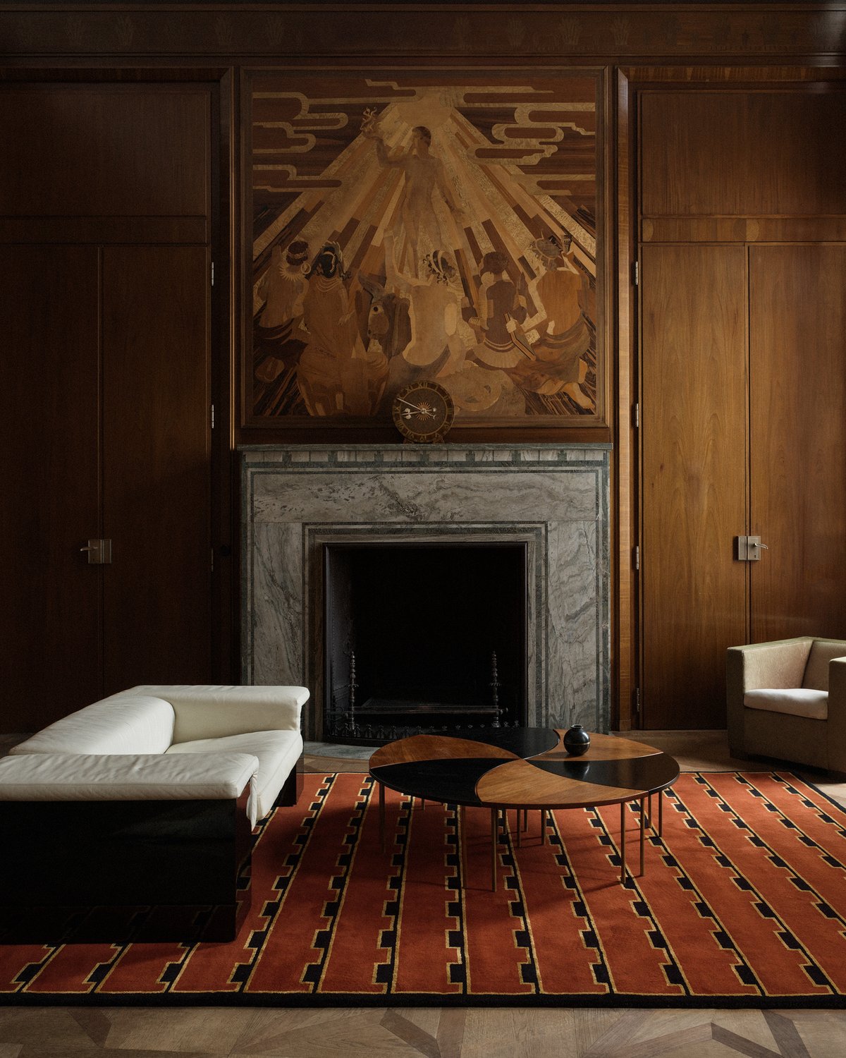 Plush wool rug Gild 02 pictured in an elegant living room with tall wood walls and a grand marble fireplace.