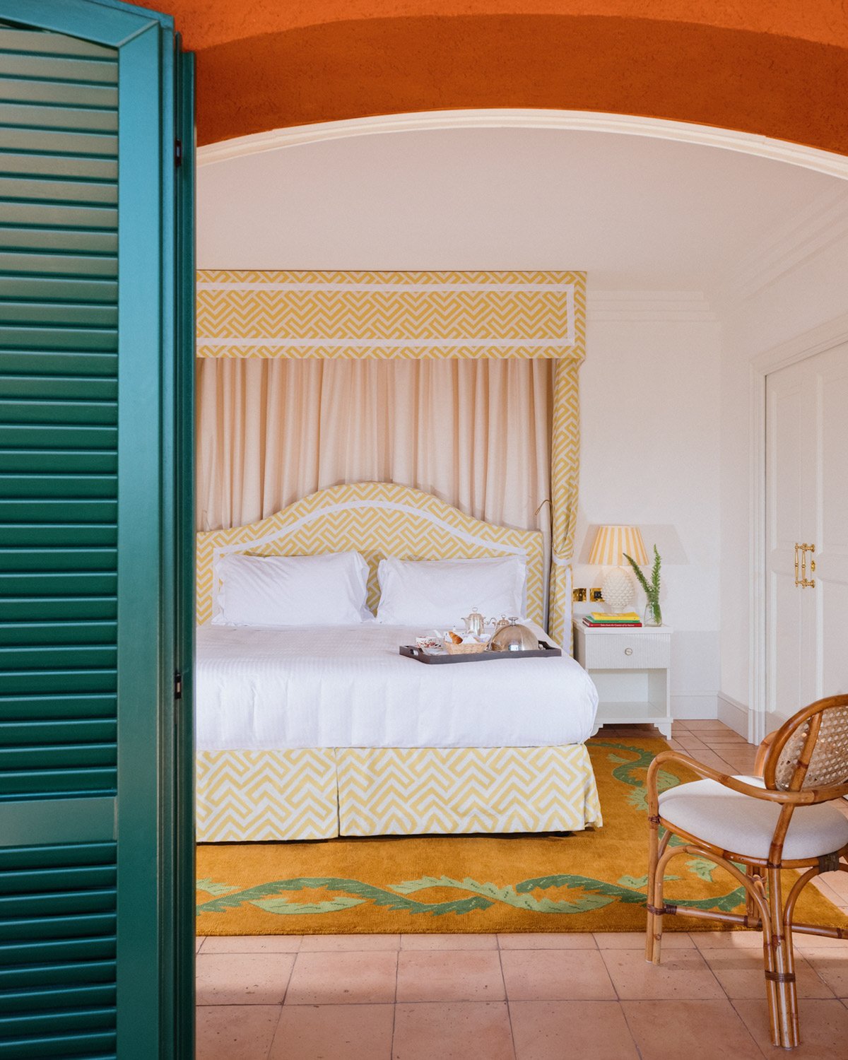 Flauschiger Wollteppich Climbing Vine ISSIMO abgebildet in einem Schlafzimmer des Hotels Il Pellicano mit cremefarbenen Details und einer türkisfarbenen Holztür.