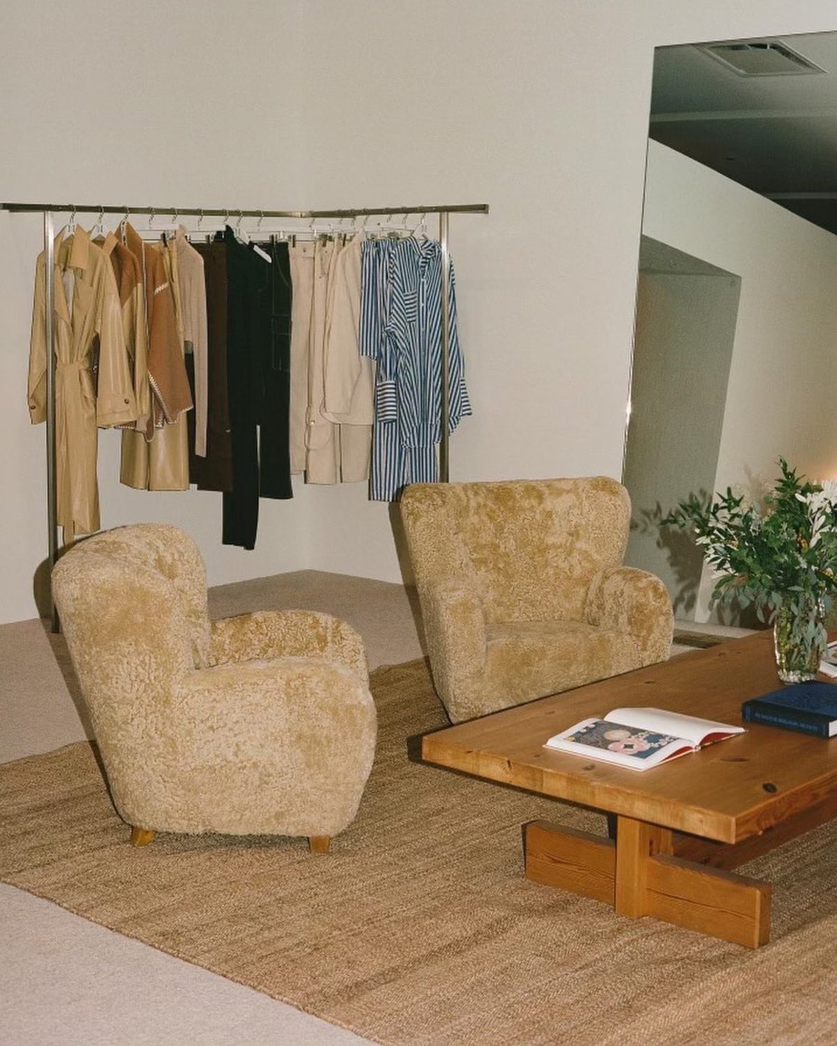 Juteteppich Corner inszeniert in einem Modeschauraum mit einem großen Spiegel, einem Couchtisch aus Holz und weichen beigefarbenen Sesseln.