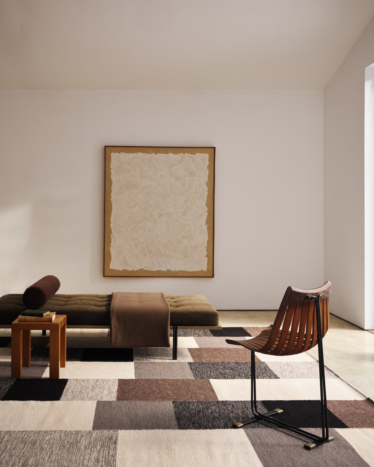 Patchwork – 02 i Black, stylad i ett vardagsrum med dagbädd. Den slätvävda mattan visar ett grafiskt mönster av tonade block.