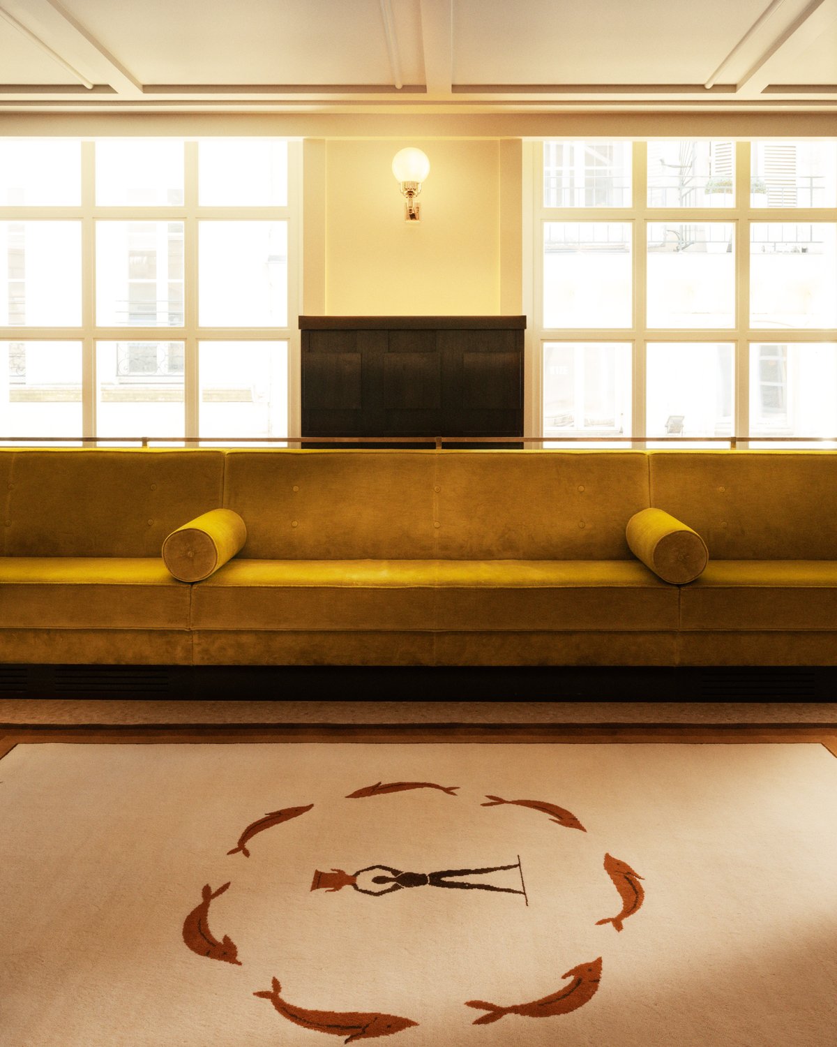 Plush wool rug designed by Parisian designer Fabrizio Casiraghi next to a beautiful yellow velvet sofa in front of large windows in Paris, France.