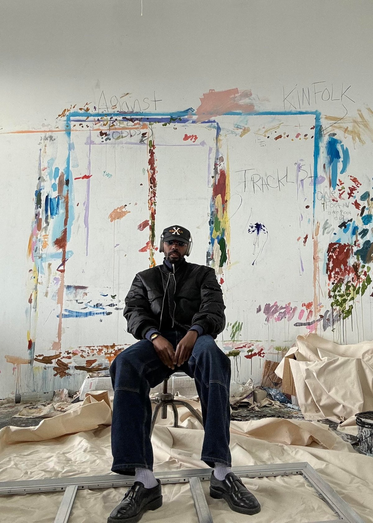 Porträt von Sissòn vor einer bemalten Wand in einem Kunststudio.