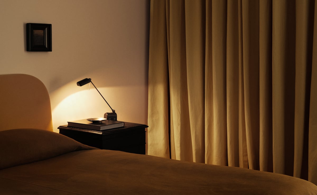 The Blackout curtains in Leo by Nordic Knots, styled in a serene bedroom with rust-toned bedding and a sleek black nightstand.