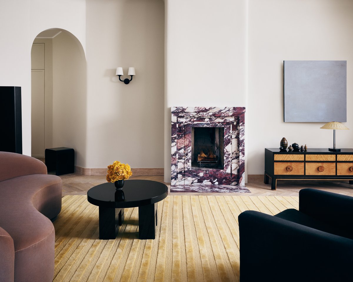 Plush wool rug Park 03 in the color Sunrise photographed in a brightly lit living room with soft muted colored furniture and a purple marble fireplace.