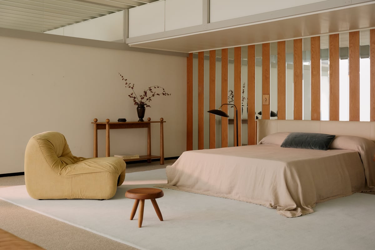 Tapis en laine moelleux Grand en Powder Blue photographié dans une chambre moderne à Los Angeles avec un fauteuil d’appoint couleur moutarde et un lit beige.