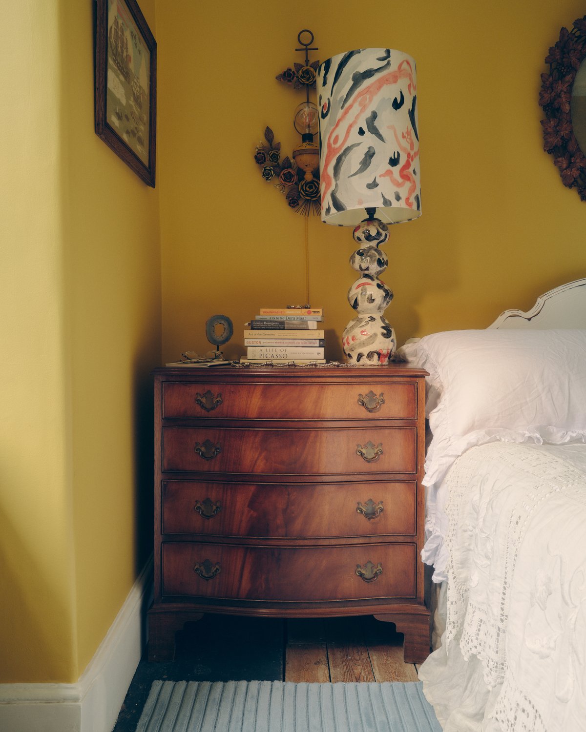 Ullmattan Park 02 i färgen Sky fotograferad bredvid ett sängbord i trä i ett sovrum med gula väggar.