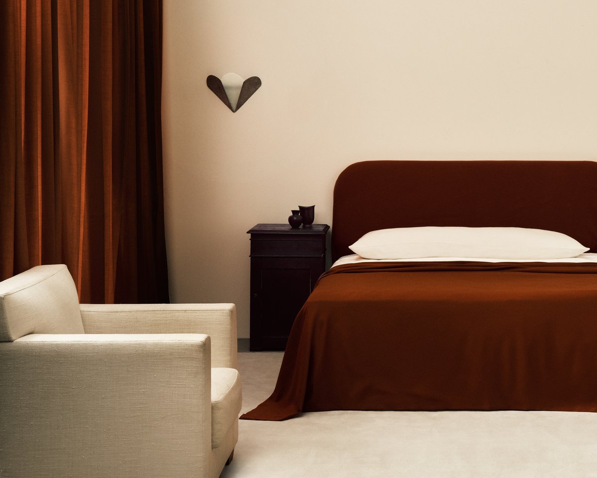 Die The Grand Vorhänge in Burnt Red abgebildet in einem wunderschönen Schlafzimmer mit schwarzen Einrichtungsdetails und einem Bett mit roten Laken.