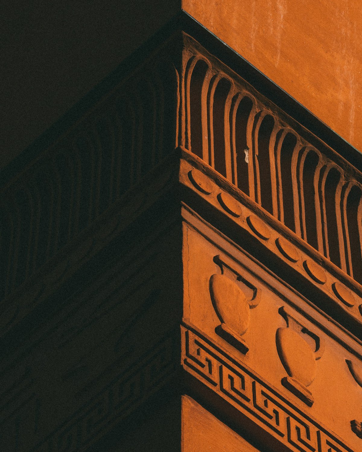 Architectural detail of a terracotta corner at Stockholm Public Library, featuring urn motifs and geometric ornamentation.