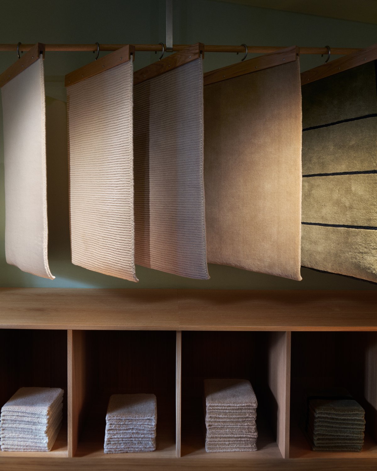 Échantillons de tapis suspendus sur un portant dans le showroom de Nordic Knots.