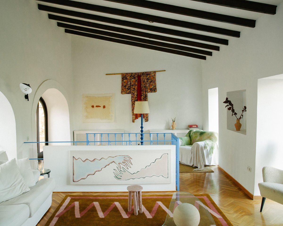 Folding Ribbon – Amber brings graphic rhythm and warmth to this eclectic space. Its bold pink lines and earthy base echo the surrounding art and architectural curves, tying the room together with playful sophistication.