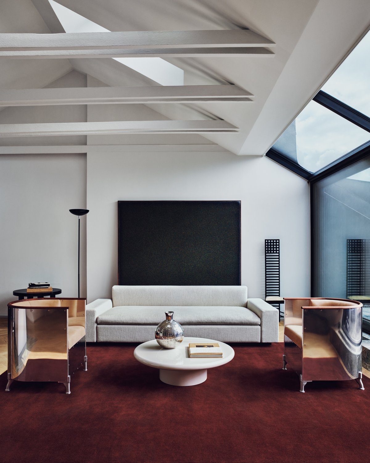 Plush wool rug Grand in Deep Wine pictured in a Stockholm apartment living room with chrome armchairs and gray sofa.