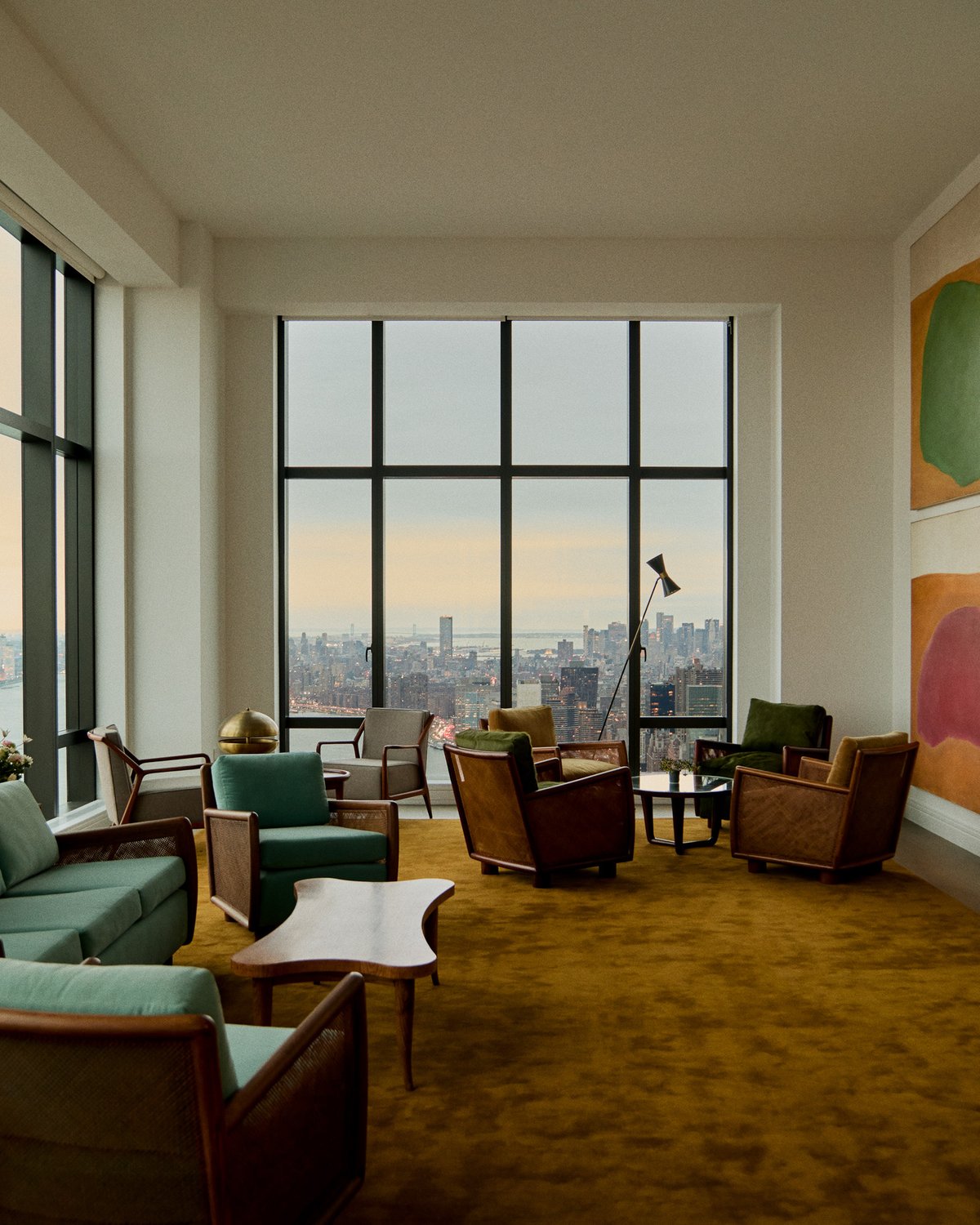 Grand rug in Leo, styled in a living room with multiple seating pieces, showing a warm golden ochre tone with a smooth surface and dense pile.