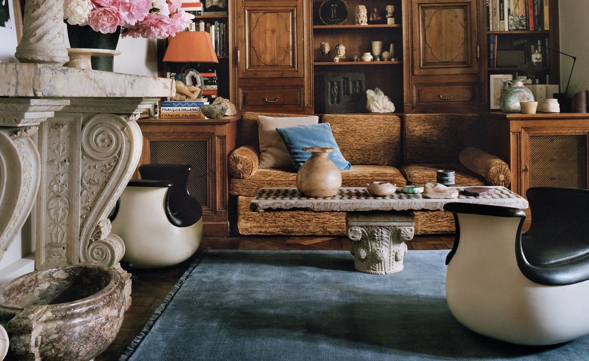 The Mohair rug in Slate Blue is shown in a Paris living room with wooden paneling, sculptural armchairs, and a marble fireplace adorned with pink flowers, creating a refined and artistic atmosphere.